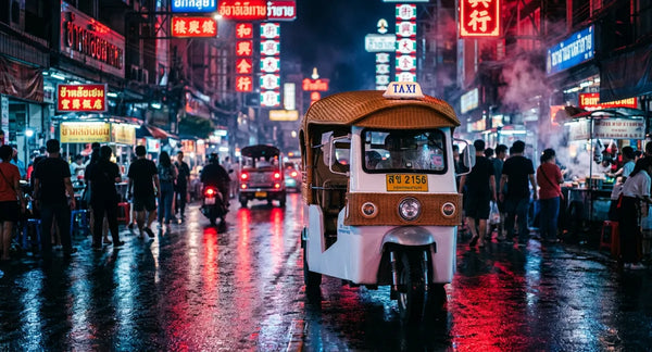Neon-lit Yaowarat road at night with tuk tuk on wet pavement