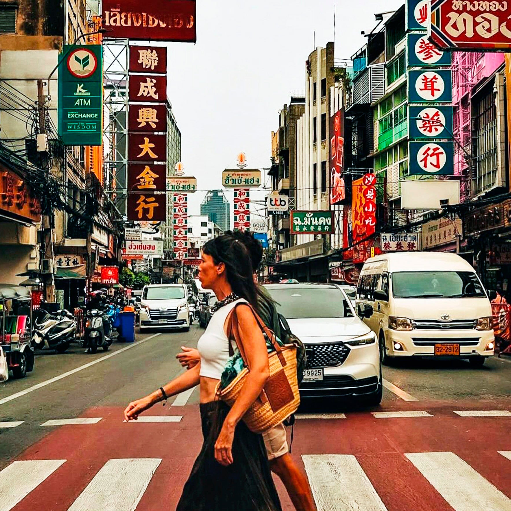 Tourists crossing Yaowarat Road in Bangkok Chinatown, explore busy street scenes with TukMe Tuk Tuk tours