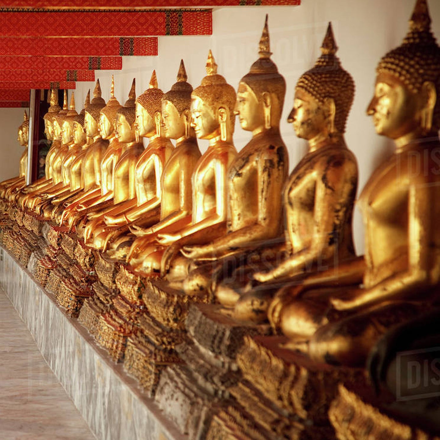 Row of golden Buddha statues at Bangkok temple, discover sacred sites with TukMe Tuk Tuk tours