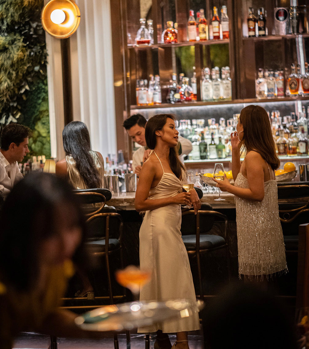 Elegantly dressed women enjoying craft cocktails at upscale Bangkok speakeasy bar with premium spirits collection - TukMe Speakeasy Bar Hopping tour nightlife experience